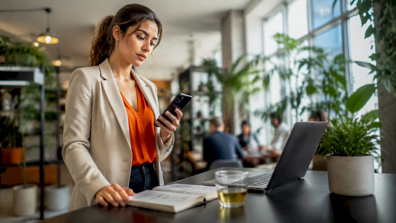 Woman managing calls on smartphone at home office desk