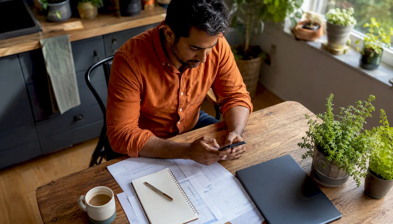 Man texting on phone in home office
